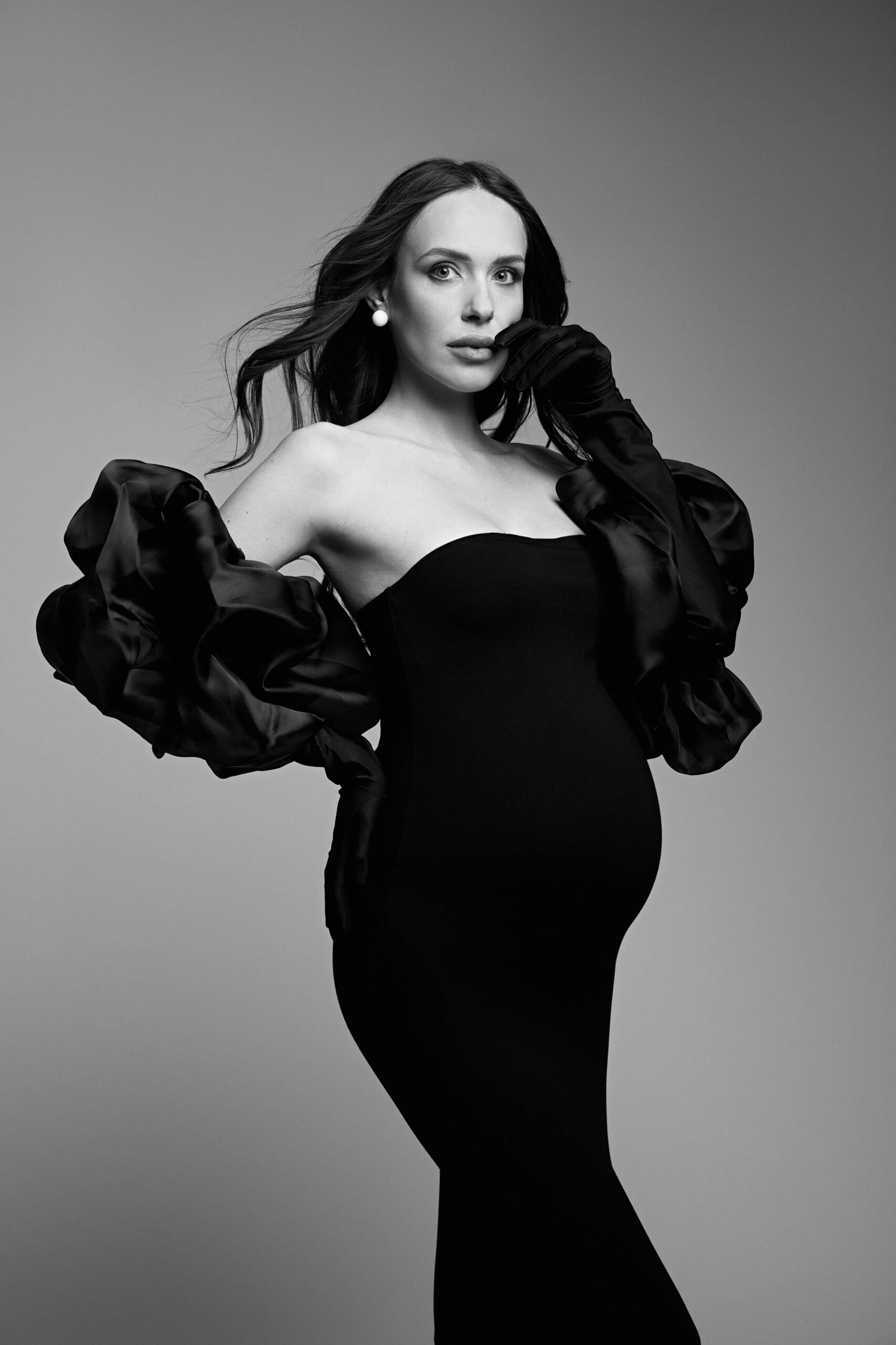 Babybauchfotografie einer schwangeren Frau im Studio in eleganter Pose im schwarzen Kleid in Bamberg